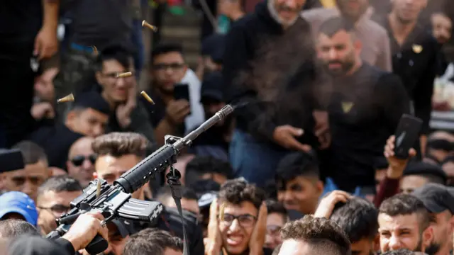 গ্রুপের একজন সদস্যের জানাজা ও দাফন অনুষ্ঠানের সময় একজন বন্দুকধারী ফাঁকা গুলি ছোড়ে।