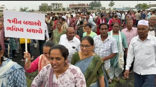 બેનર સાથે સભાસ્થળ પર આવતા ખેડૂતો 