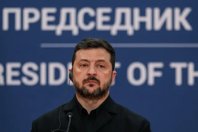 Зеленський перед мікрофоном, позаду написи сербською мовою