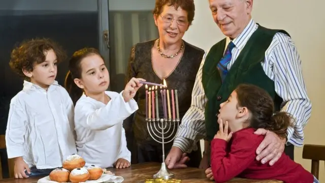 Familia zikisherehea Hanukkah kwa kuwasha mishumaa tisa -kila mshumaa ukiwashwa usiku wa kila siku katika sherehe