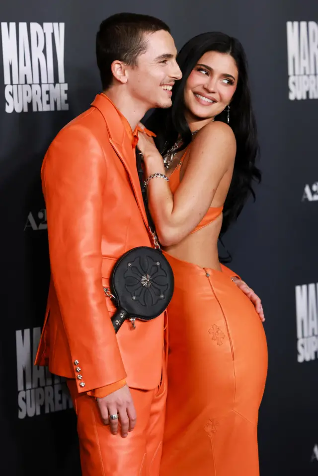 Chalamet w pomarańczowym garniturze i Kylie Jenner w pasującej pomarańczowej sukience. Stoją obok siebie i czule się uśmiechają.