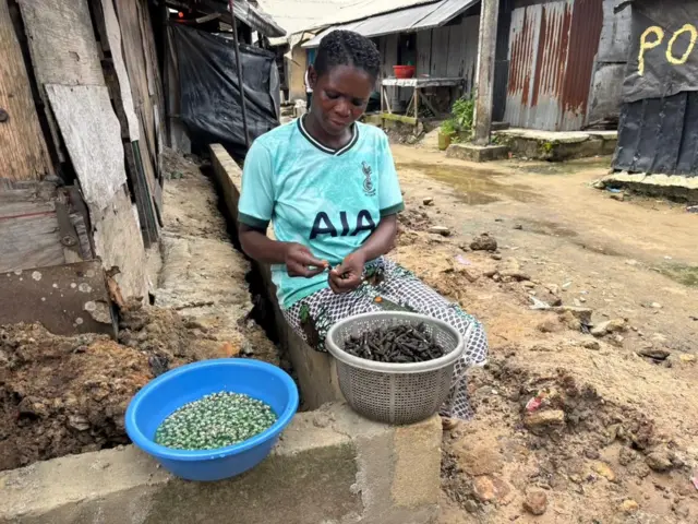 Lydia Ibifubara Gilbert dey remove periwinkle from di shells dey put for basin wey she go sell.