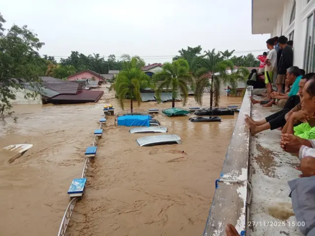 Situasi banjir di Aceh Tamiang pada hari kedua, Kamis (27/11). Arif, keluarganya, dan belasan koleganya mengungsi ke masjid. Dari lantai dua masjid, warga menyaksikan banjir menenggelamkan rumah-rumah dan kendaraan. 