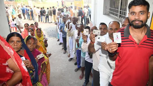 बिहार चुनाव में मतदान के लिए लाइन में लगे महिला और पुरुष मतदाता
