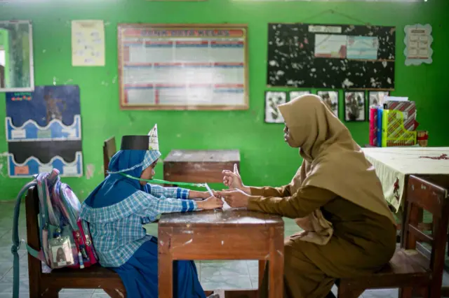 Seorang guru mengajar satu siswa baru saat Masa Pengenalan Lingkungan Sekolah (MPLS) di SD Negeri Cepokosawit II, Boyolali, Jawa Tengah, Senin (13/07).