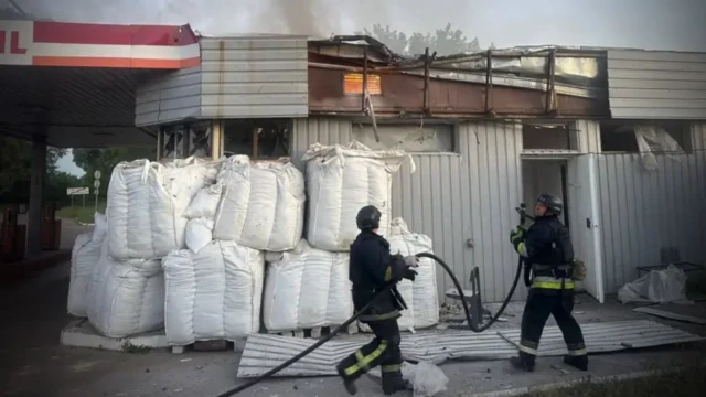 Двое спасателей на фоне АЗС, обложенной большими белыми мешками в два ряда