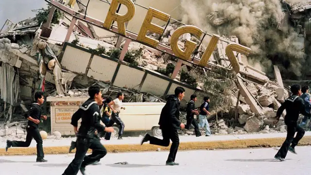 Personas corren cerca de un edificio colapsado por el terremoto de 1985