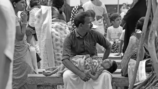 কাসারগড়ে একটি সরকারি মেডিক্যাল শিবিরে ছেলেকে নিয়ে অপেক্ষা করছেন এক বাবা। ২০১৭ সালে এই শিবিরটির আয়োজন করা হয়েছিল ওই কীটনাশক বিপর্যয়ে ক্ষতিগ্রস্তদের চিহ্নিত করতে, যাতে তাদের চিকিৎসা আর ক্ষতিপূরণের ব্যবস্থা করা যায়