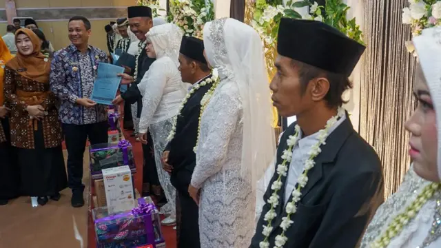 Wali Kota Pekalongan Afzan Arslan Djunaid (kedua kiri) didampingi Ketua Tim Penggerak Pembinaan Kesejahteraan Keluarga (TP PKK) Inggit Soraya (kiri) menyerahkan berkas nikah kepada pasangan pengantin