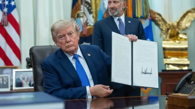 Трамп в Овальном кабинете держит в руках подписанный им указ