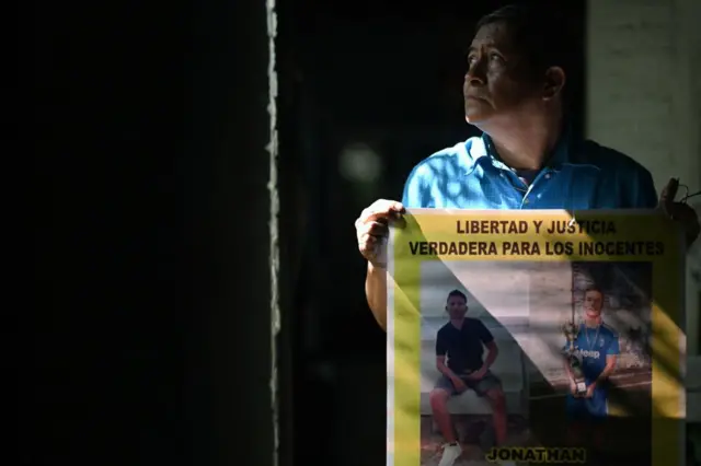Reynaldo Santos Vanegas muestra un cartel con fotos de su hijo Jonathan Santos Castillo, arrestado durante el estado de emergencia decretado por el gobierno salvadoreño para combatir a un grupo criminal, durante una entrevista en Soyapango, el 25 de octubre de 2024.