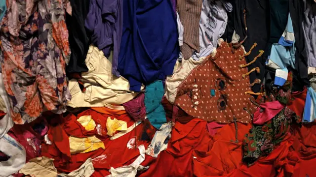 Des textiles colorés et d'autres matériaux trouvés, formant une scène abstraite représentant une silhouette allongée sur le sol.