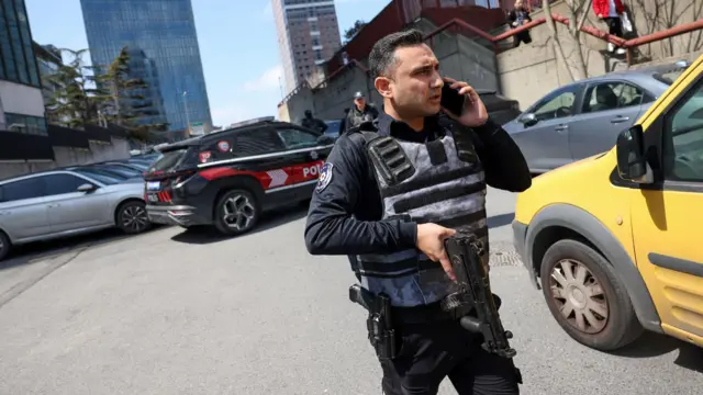 Policajac sa automatskom puškom ispred automobila