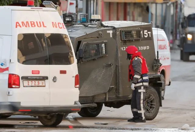 مركبة عسكرية إسرائيلية بجوار سيارة إسعاف في جنين بالضفة الغربية المحتلة، 21 يناير/كانون الثاني 2025