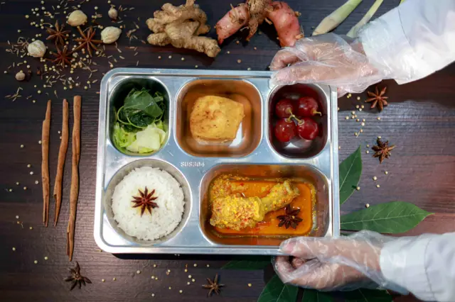 Ahli gizi menyiapkan paket makanan menu kuliner nusantara untuk program Makan Bergizi Gratis (MBG) di Satuan Pelayanan Pemenuhan Gizi (SPPG) Dipan Tanjunganom, Nganjuk, Jawa Timur, Kamis (8/1/2026). Pada distribusi MBG hari pertama masuk sekolah usai libur, SPPG Dipan Tanjunganom menyajikan menu masakan nusantara dan lokal berupa ayam gulai daun singkong dengan kandungan gizi yang seimbang kepada 2.841 penerima manfaat di kawasan tersebut. ANTARA FOTO/Muhammad Mada/nz