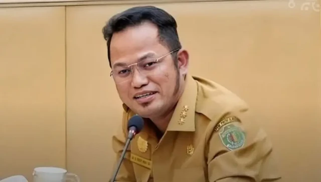 Gubernur Kaltim Rudy Mas'ud menggunakan pakaian dinas berwarna cokelat dan berkacamata sedang menatap ke arah kamera.