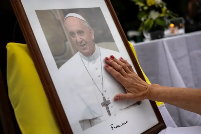 Pessoa coloca mão em quadro do papa Francisco