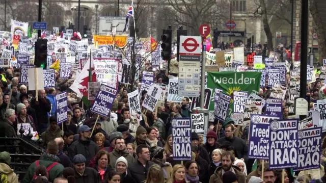 Толпа людей в центре Лондона с плакатами против войны в Ираке