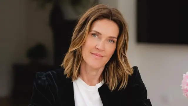 Omzunun hemen altında sarı röfleli dalgalı saçları olan Emma Bardwell'in portresi. Beyaz bir tişört ve siyah kadife ceket giymiş, gülümsüyor.</p><p>