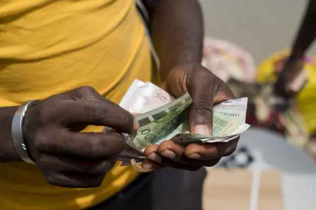 Une main compte des billets en CFA de l'Afrique de l'Ouest