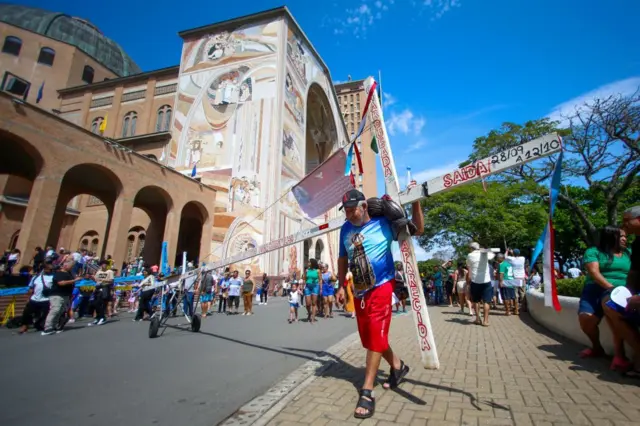 Um devoto carrega uma cruz enquanto presta homenagem a Nossa Senhora Aparecida, na basílica de mesmo nome em Aparecida, em 12 de outubro de 2024.