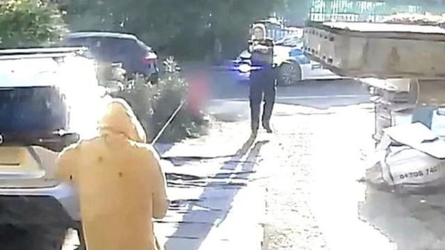 Policial diante de homem com capuz amarelo