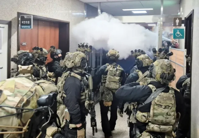 윤석열 대통령이 비상계엄을 선포한 가운데, 무장 군인들이 국회 본관으로 진입하자 국회 보좌진들이 소화기를 뿌리고 있다