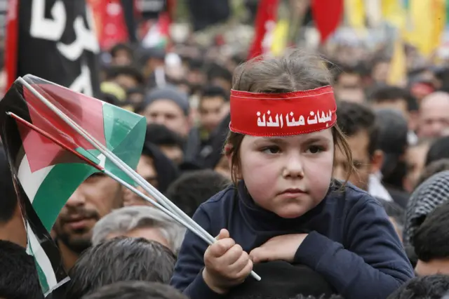 طفلة تضع عصبة كتب عليها "هيهات منا الذلة" خلال موكب عاشورائي، في شعار يلخص المعنى الذي يربطه الشيعة بكربلاء: رفض الخضوع حتى عندما يكون الثمن كبيراً.