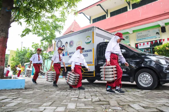 Sejumlah pelajar membawa Makanan Bergizi Gratis (MBG) yang disediakan Satuan Pelayanan Pemenuhan Gizi (SPPG) Polres Gresik di SDN 49, Yosowilangun, Gresik, Jawa Timur, Senin (17/11).