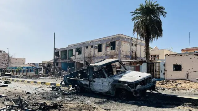 Un pick-up incendié à l'extérieur de l'hôpital universitaire Al-Shaab à Khartoum après de violents combats entre l'armée et les forces de sécurité - mars 2025.