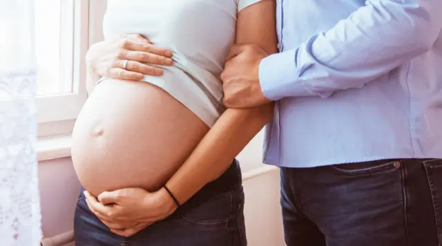 Barrigabet 365 pagauma mulher branca grávida com mão masculina branca segurando seu braço