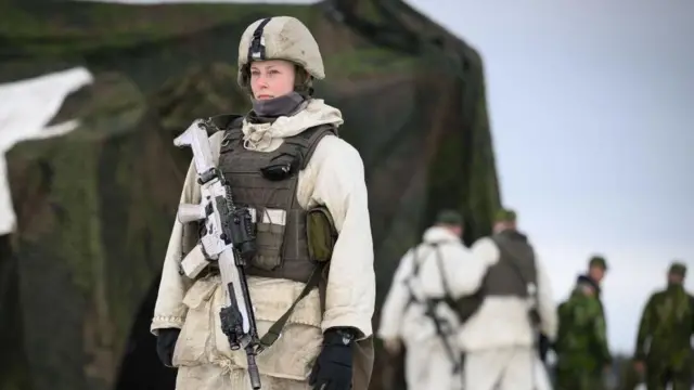 Żołnierka ze szwedzkiego pułku logistycznego pełni wartę przy magazynie zaopatrzenia podczas ćwiczeń wojskowych Nordic Response 8 marca 2024 roku w okolicach Enontekio w Finlandi