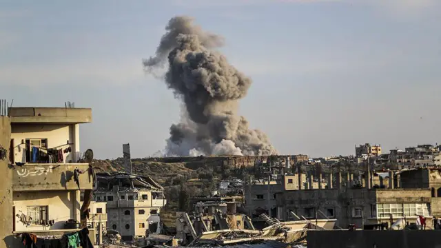 Smoke rises behind damaged buildings in Gaza City after an Israeli strike in the area.