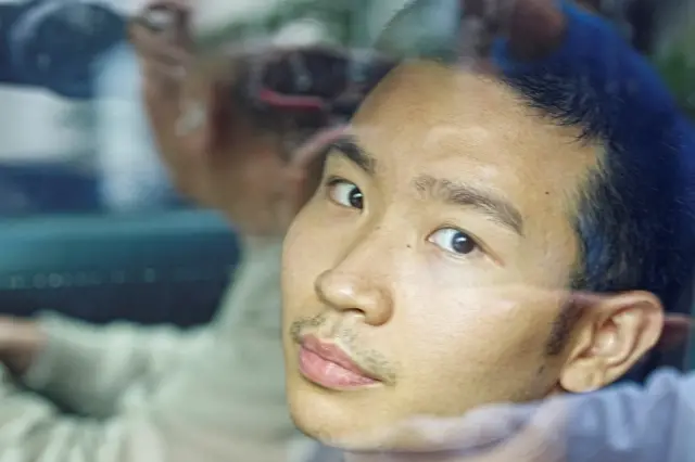 2025年12月1日，24岁的关靖丰被拘留后离开警署。