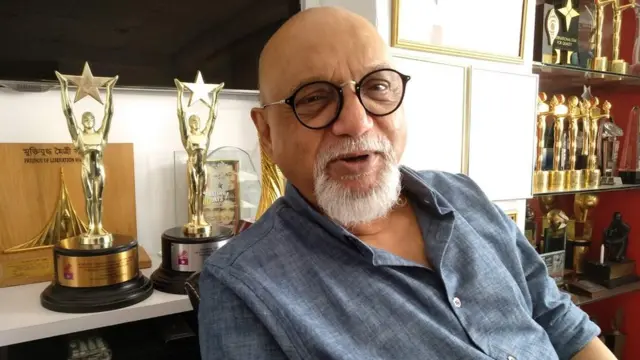 প্রীতীশ নন্দী। পেছনে তার পাওয়া 'মুক্তিযুদ্ধ মৈত্রী সম্মাননা'