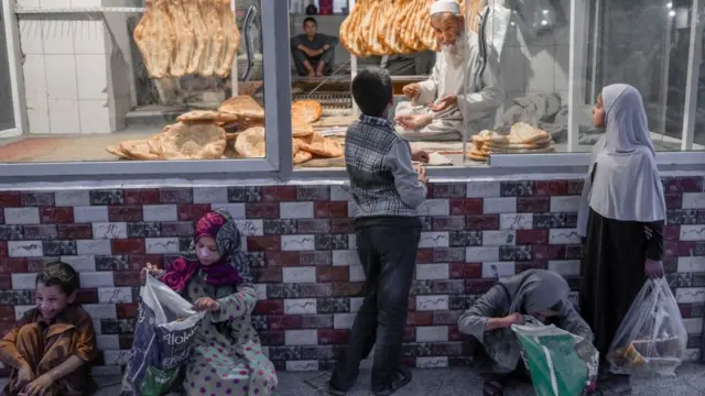 Seorang anak membeli roti saat beberapa anak menunggu roti gratis di depan sebuah toko roti di Kabul pada 14 September 2021.