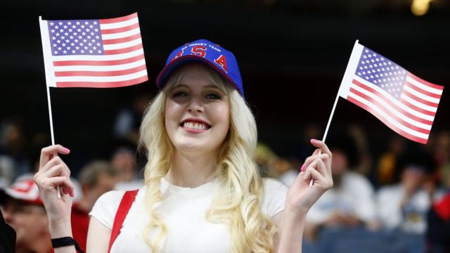 Una mujer sostiene banderas de Estados Unidos