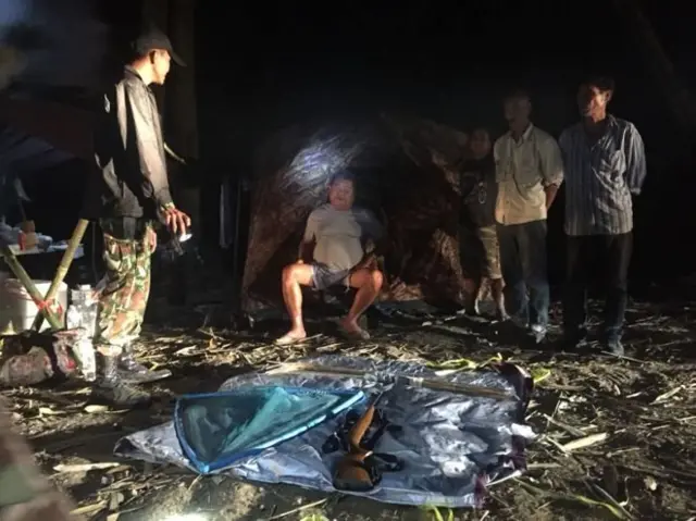 ภาพถ่ายนายเปรมชัย กรรณสูต (นั่งตรงกลาง) ขณะที่ถูกเจ้าหน้าที่เขตรักษาพันธุ์สัตว์ป่าทุ่งใหญ่นเรศวรจับกุมตัว