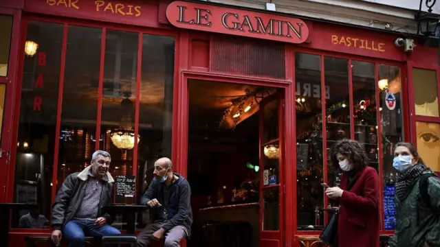 Paris'te bir barın önünde oturanlar.