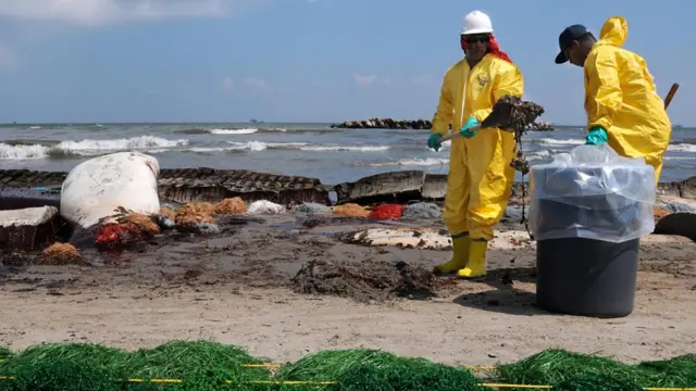 Dos hombres hacen labores de limpieza tras el vertido petrolero en el golfo de México