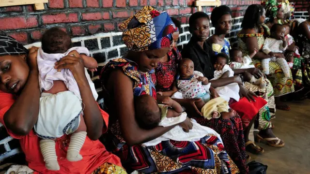 แม่อุ้มเด็กต่อแถวเพื่อพบหมอ