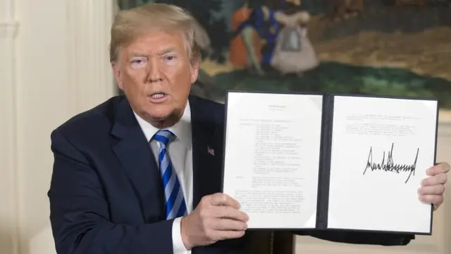 Donald Trump holding aloft an order he signed withdrawing the US from the Iran nuclear deal
