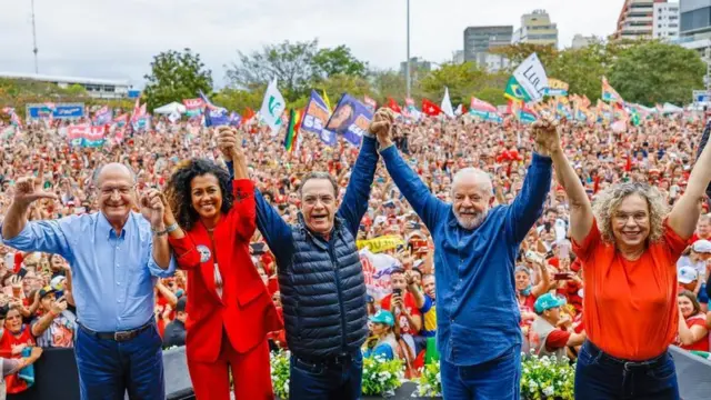 Políticos posam com multidão no fundo