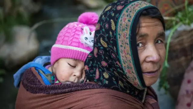 Criança dormindo nas costas da mãe