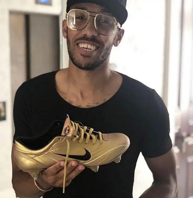 Pierre-Emerick Aubameyang tenant une chaussure de football