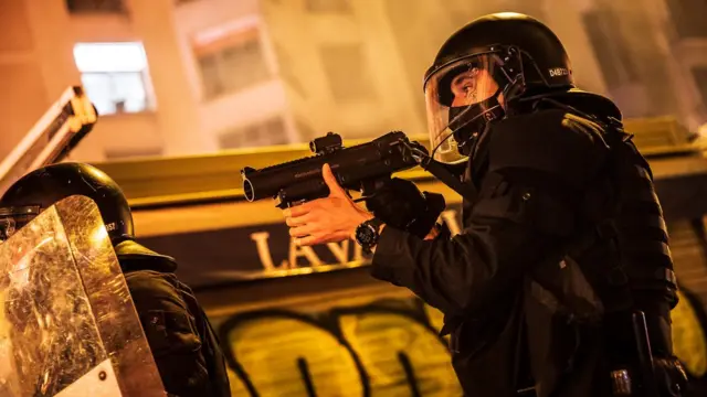 Un policía apunta con su arma de proyectiles de goma.