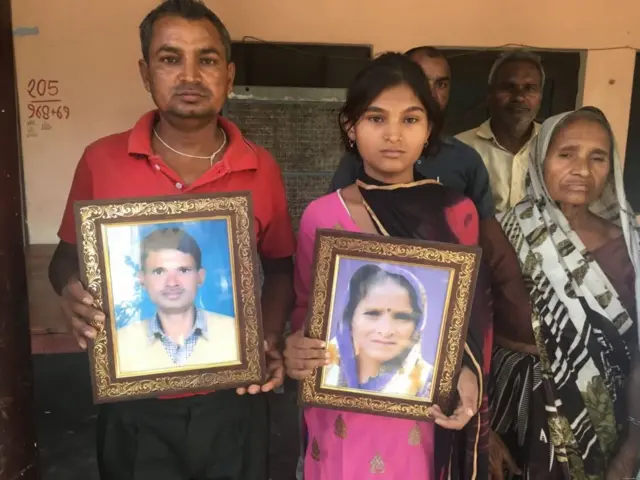 મૃતક ખેડૂતોની તસવીરો લઈને ઊભેલાં લલિત અને ભાવના