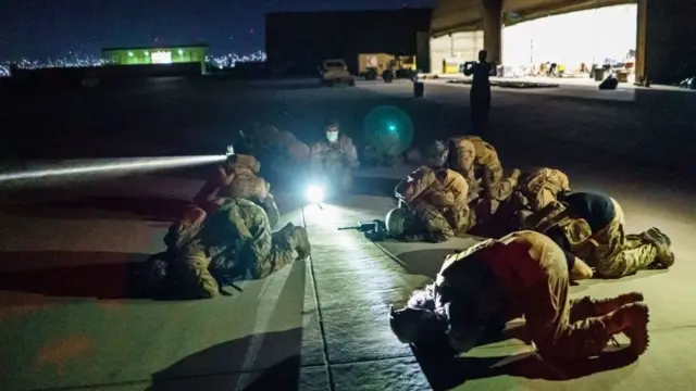 ทหารตาลีบันในเครื่องแบบทหารอเมริกันสวดมนต์บนพื้นสนามบิน