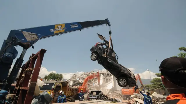 Alat berat memindahkan kendaraan yang hancur tertimpa puing bangunan Hotel Roa-roa, Palu.