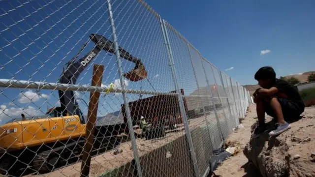 Niño frente a una valla fronteriza en México